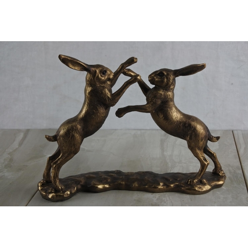 73 - A resin figure of bronzed boxing hares. Approx 27x19cm.