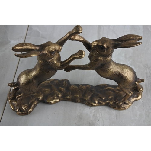 73 - A resin figure of bronzed boxing hares. Approx 27x19cm.