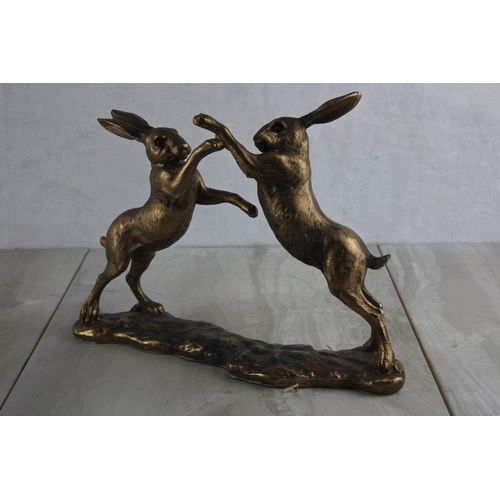 73 - A resin figure of bronzed boxing hares. Approx 27x19cm.