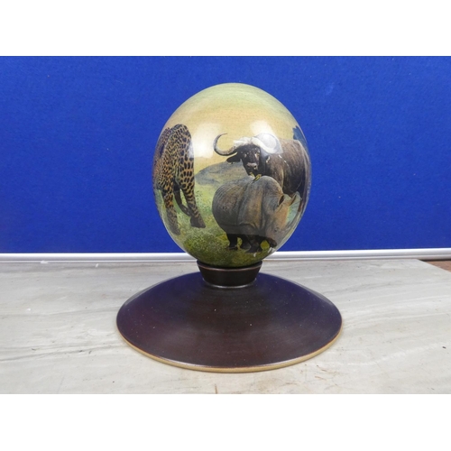 208 - A stunning hand painted ostrich egg decorated with wild animals on a presentation stand.