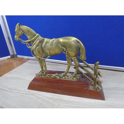 219 - A brass ornament of a horse mounted on a wooden plinth.  Approx 16cm.