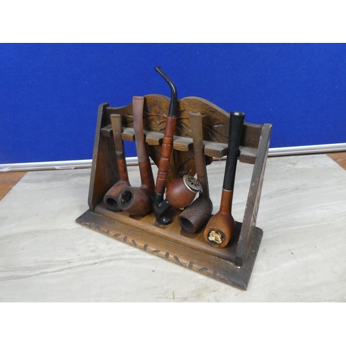 278 - An antique oak pipe stand and a collection of five pipes.