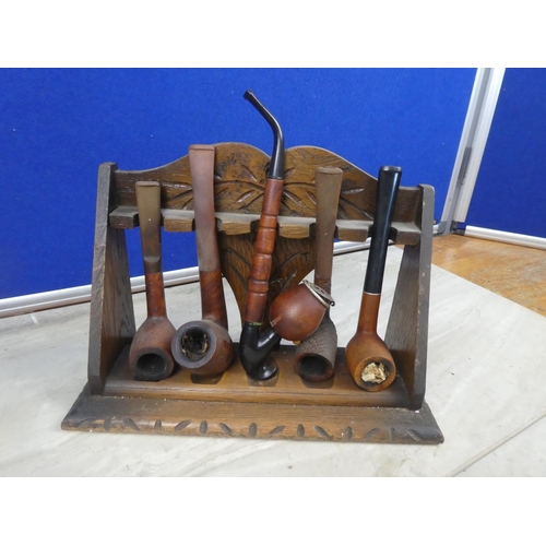 278 - An antique oak pipe stand and a collection of five pipes.