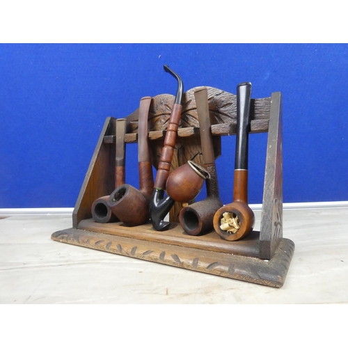 278 - An antique oak pipe stand and a collection of five pipes.