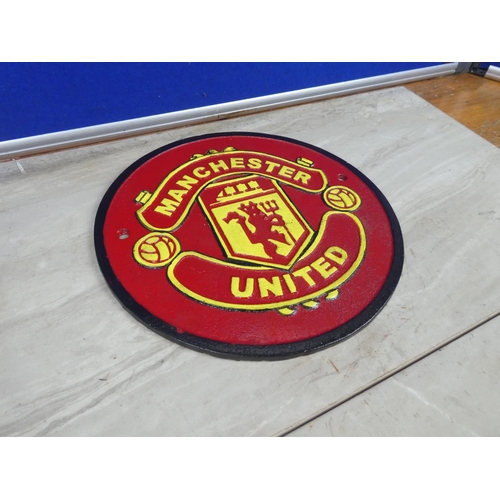 320 - A Manchester United cast iron plaque.  Approx 24cm dia.