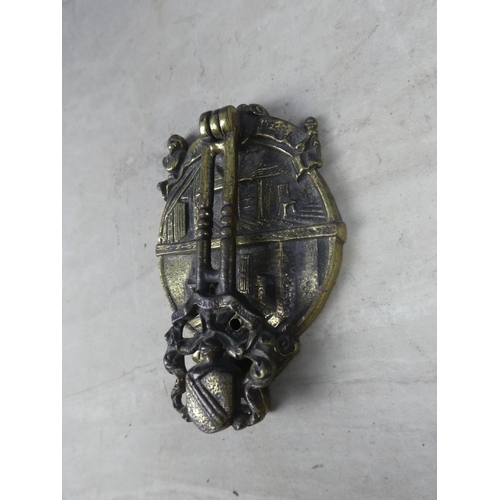 329 - A brass door knocker in the style of a house with crest.