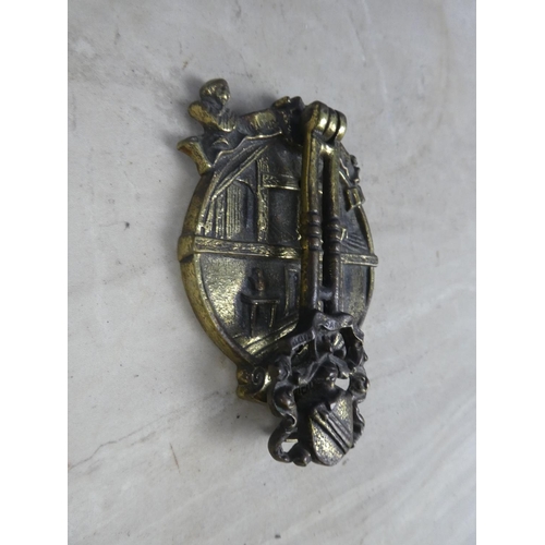 329 - A brass door knocker in the style of a house with crest.