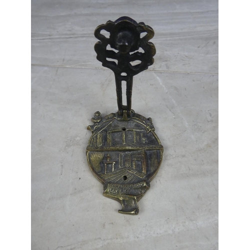 329 - A brass door knocker in the style of a house with crest.