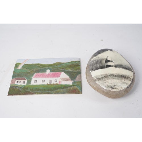 356 - A pebble stone with a painting of lighthouse and another hand painted tile of a cottage.