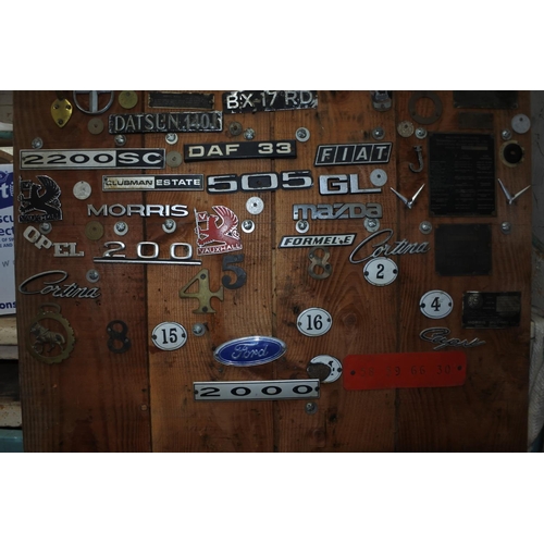 622 - A pine door with a large selection of vintage car badges and mascots.