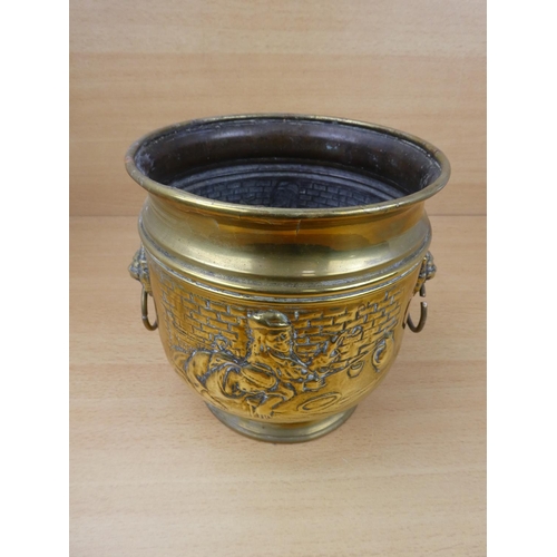 513 - A vintage brass plant pot with lion mask handles.