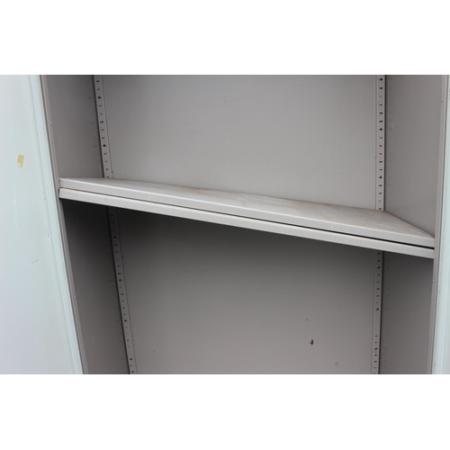 574 - A large two door metal cabinet with shelves.