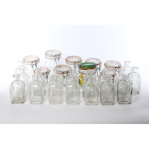 128 - A large assortment of glass bottles and storage jars.