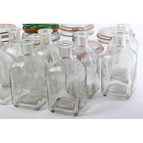 128 - A large assortment of glass bottles and storage jars.