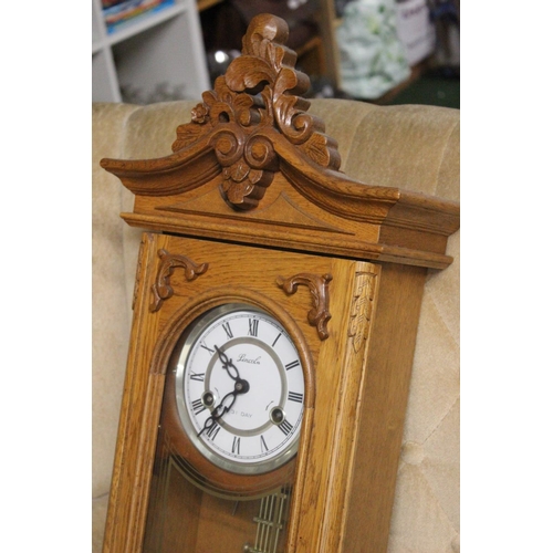 220 - A Lincoln wood cased 31 day regulating wall clock. Approx  70cm.