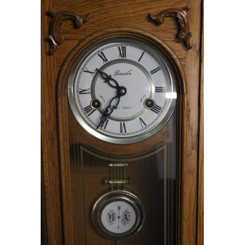 220 - A Lincoln wood cased 31 day regulating wall clock. Approx  70cm.