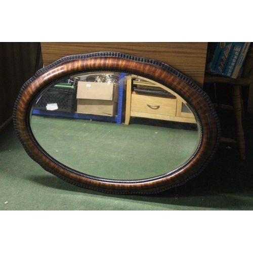 264 - An antique oval mirror with bevelled glass & wooden frame.