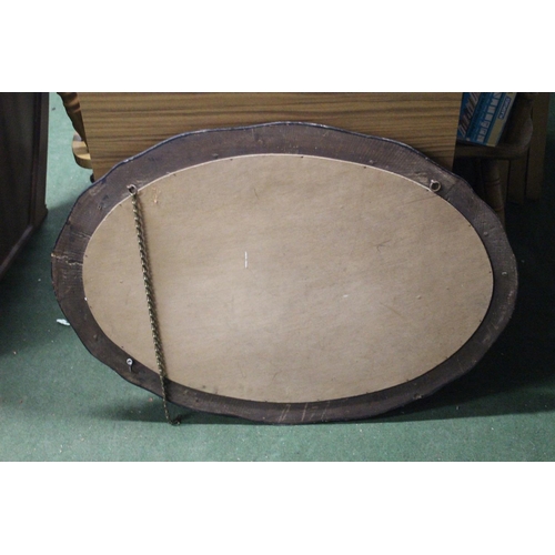 264 - An antique oval mirror with bevelled glass & wooden frame.