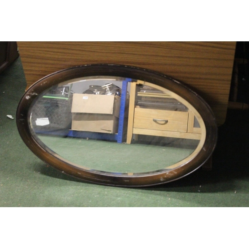 265 - An antique oval mirror with bevelled glass & wooden frame.