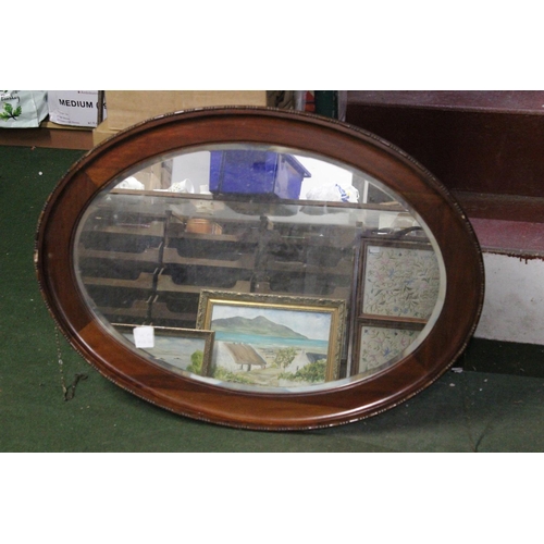 454 - An antique oval mirror with bevelled glass.