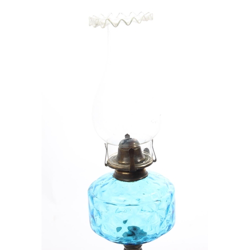 374 - An antique oil lamp with a diamond patterned turquoise font and a shield patterned cast iron base. M... 