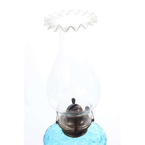 374 - An antique oil lamp with a diamond patterned turquoise font and a shield patterned cast iron base. M... 