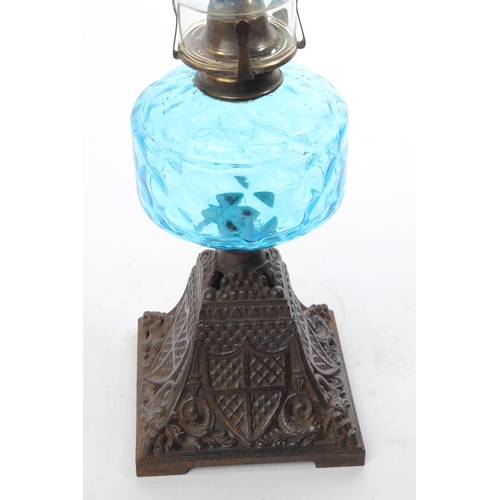 374 - An antique oil lamp with a diamond patterned turquoise font and a shield patterned cast iron base. M... 