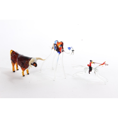 149 - A collection of vintage glass animal figures to include a camel, horse and jockey and a bull.