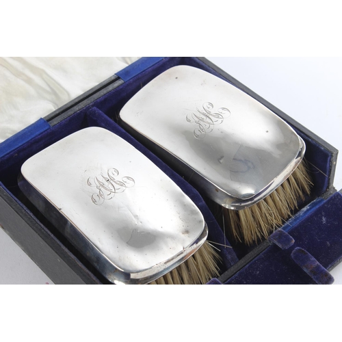 153 - A cased pair of antique silver mounted engraved dressing table brushes.