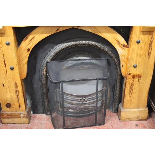 416 - A chunky pine fireplace surround with cast iron inset and fireguard.