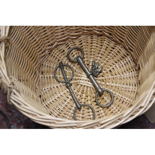 492 - A wicker basket containing a lot horse bridle gear.