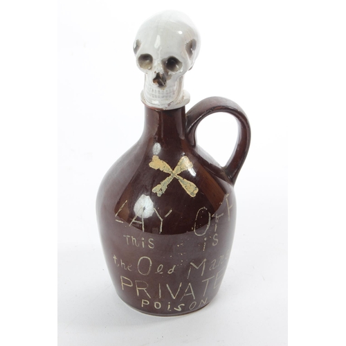 An unusual Japanese ceramic decanter 'Lay Off this - Is the Old Mans Private Poison' with skull head stopper.