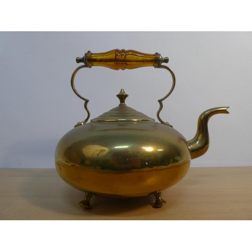 66 - A vintage brass kettle with amber glass handle.