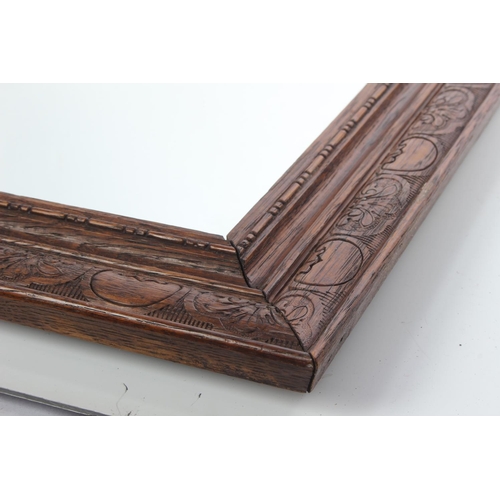 221 - An oak framed wall mirror with carved detail to frame.