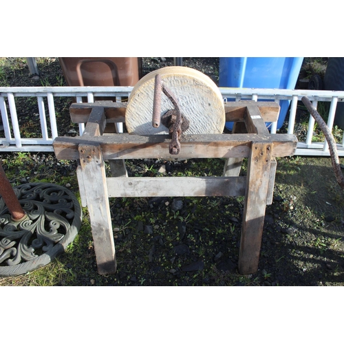 12 - An antique grindstone on wooden base.