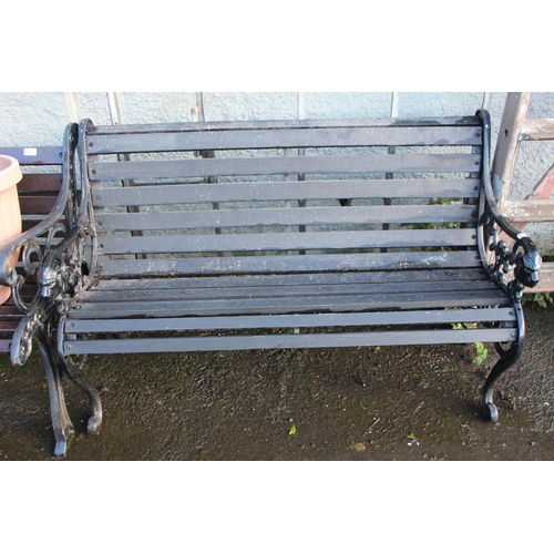 33 - An antique garden bench with cast iron ends with lion head details.