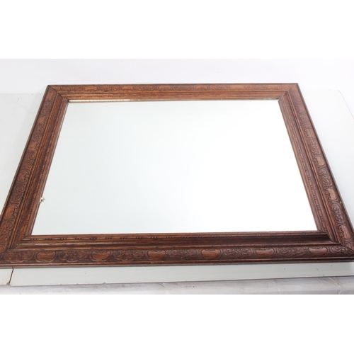 221 - An oak framed wall mirror with carved detail to frame.