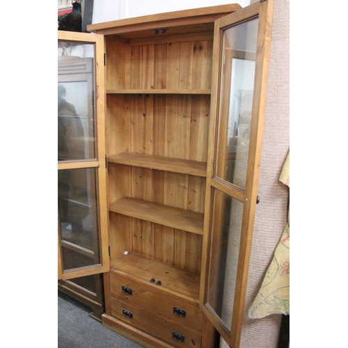 483 - A large modern bookcase with glass doors, measuring 31.5x11.5x73inches.