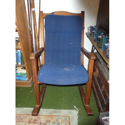 137 - A large heavy wooden rocking chair with cushion.