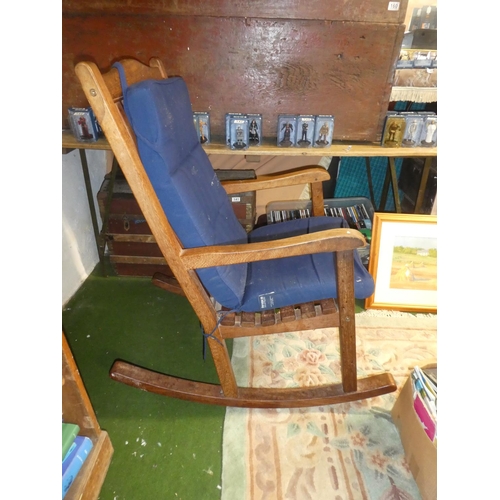 137 - A large heavy wooden rocking chair with cushion.