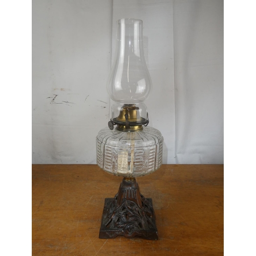 211 - An antique oil lamp with clear glass font on decorative cast iron base.