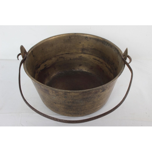 197 - An antique brass preserving saucepan with original handle, measuring 25cm wide.