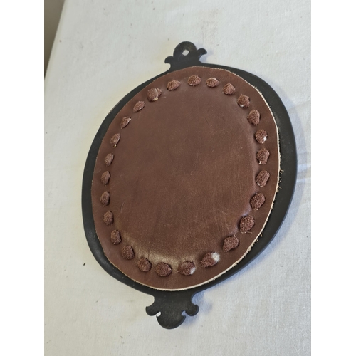 463 - An unusual leather framed mirror with decorative design.