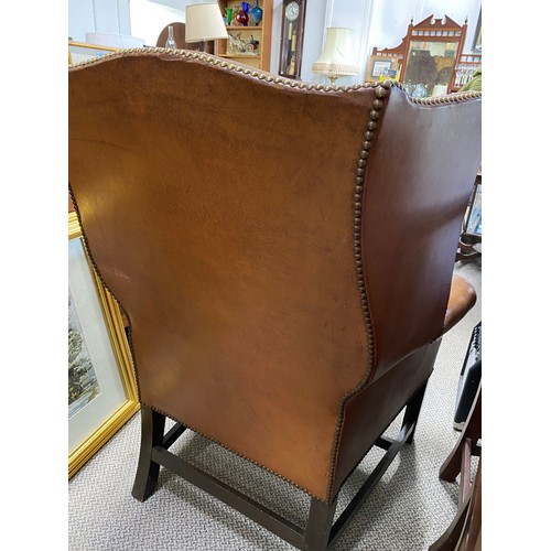 183 - A stunning antique leather upholstered winged backed armchair.