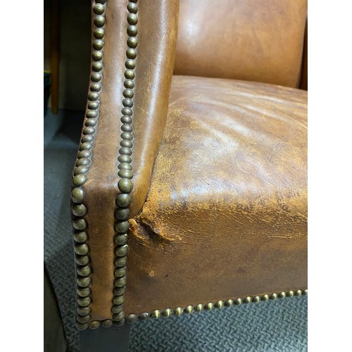 183 - A stunning antique leather upholstered winged backed armchair.