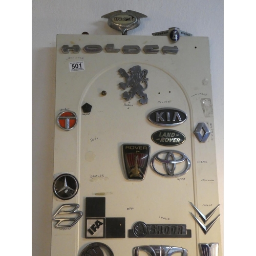 501 - A lot of vintage car badges mounted on a wooden panel.