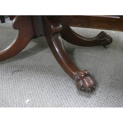 552 - An antique mahogany drop leaf dining table on centre pedestal with claw feet detail.