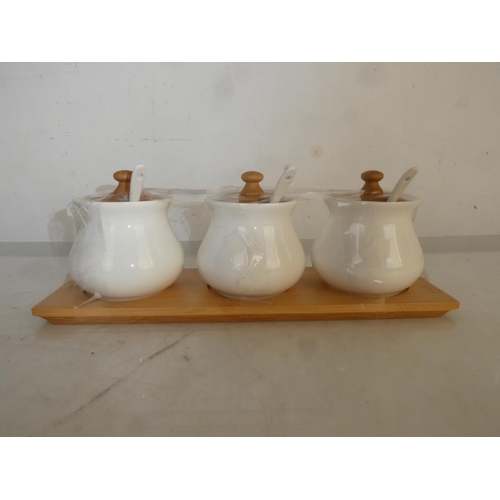 86 - A three ceramic condiment set on a wooden tray.