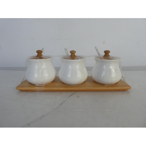 86 - A three ceramic condiment set on a wooden tray.