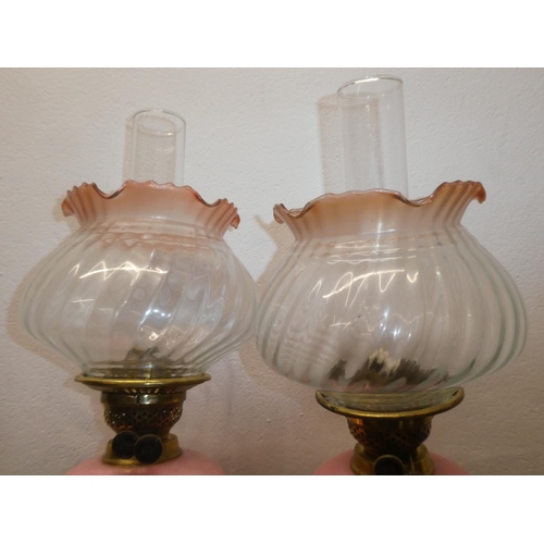 118 - A stunning pair of antique brass oil lamps with pink marble glaze fonts, measuring 29